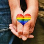 Rainbow heart drawing on hands, LGBTQ love symbol, gay couple hand in hand, lovers