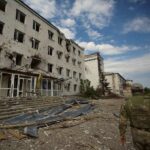 A Ukrainian serviceman walks next to a building damaged by a Russian military strike, as Russia