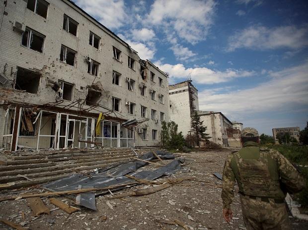 A Ukrainian serviceman walks next to a building damaged by a Russian military strike, as Russia