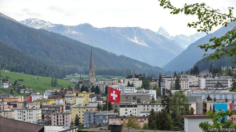 A Swiss national flag above the town ahead of the World Economic Forum (WEF) in Davos, Switzerland, on Saturday, May 21, 2022. The annual Davos gathering of political leaders, top executives and celebrities runs from May 22 to 26. Photographer: Hollie Adams/Bloomberg via Getty Images