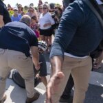 President Joe Biden is helped by U.S. Secret Service agents after falling from his bike as he stopped to greet a crowd on a trail at Gordons Pond in Rehoboth Beach, Del., Saturday, June 18, 2022. (AP Photo/Manuel Balce Ceneta)