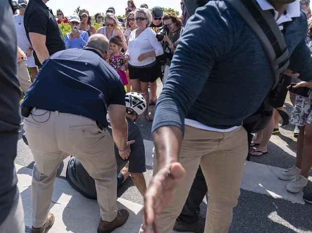 President Joe Biden is helped by U.S. Secret Service agents after falling from his bike as he stopped to greet a crowd on a trail at Gordons Pond in Rehoboth Beach, Del., Saturday, June 18, 2022. (AP Photo/Manuel Balce Ceneta)