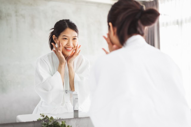 Woman in bathroom aleaning her face