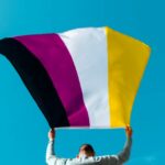 person waving a non-binary pride flag