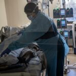 A health care worker attends to a COVID-19 patient at the Brooklyn Hospital Center in New York, Jan. 12, 2022. (Victor J. Blue/The New York Times)