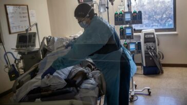 A health care worker attends to a COVID-19 patient at the Brooklyn Hospital Center in New York, Jan. 12, 2022. (Victor J. Blue/The New York Times)