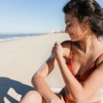 Woman applying sunscreen at beach on sunny day