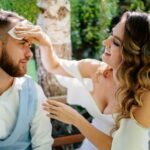 bride gently and carefully wipes the face of the groom away sweat