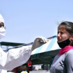 A healthcare worker collects a nasal sample of a passenger for the COVID-19 testing, amid a surge in the Coronavirus cases, at a Railway Station, in Bikaner.