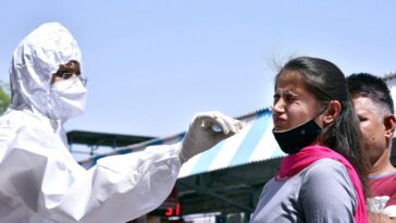 A healthcare worker collects a nasal sample of a passenger for the COVID-19 testing, amid a surge in the Coronavirus cases, at a Railway Station, in Bikaner.