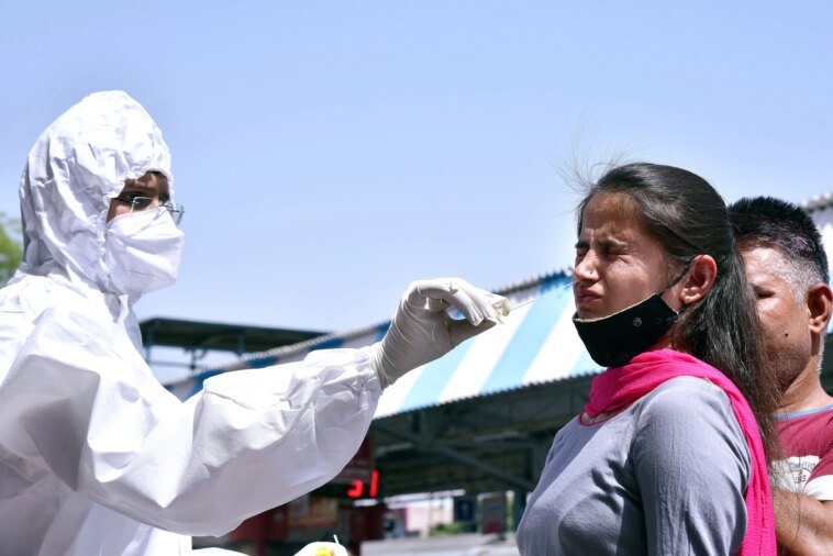 A healthcare worker collects a nasal sample of a passenger for the COVID-19 testing, amid a surge in the Coronavirus cases, at a Railway Station, in Bikaner.