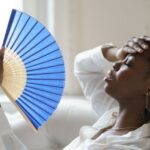 Close-Up Of Tired Woman Holding Hand Fan At Home