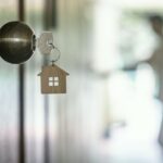 House key with home keyring in keyhole on wood door, copy space