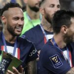 Neymar holds the trophy as he celebrate with Lionel Messi