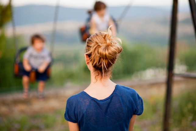 Mother looking her kids having fun in a playground