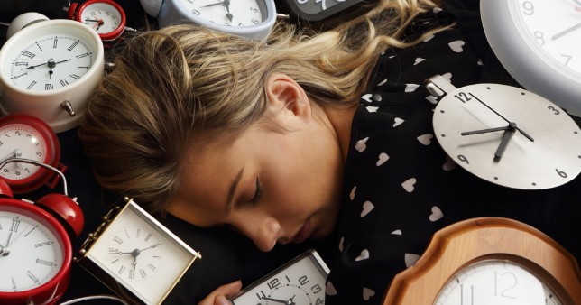 Image shows a woman lying down, surrounded by lots of different clocks.