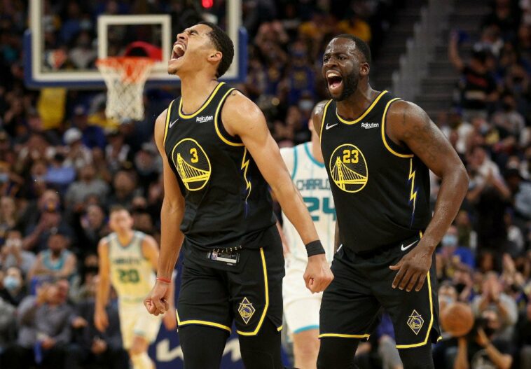 Jordan Poole #3 and Draymond Green #23 of the Golden State Warriors react after Poole made a three-point basket against the Charlotte Hornets in the first half at Chase Center on November 03, 2021 in San Francisco, California