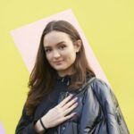 Young woman with hand on heart looking to camera.