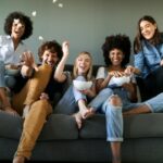 Exuberant friends sitting on couch throwing popcorn