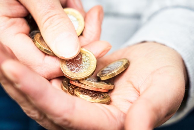 A hand counting out a pile of coins