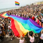 A giant rainbow Pride flag is carried along the sea front during Brighton Pride