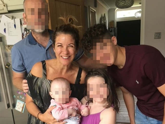 Jacqui Doyle in a kitchen with her family members. The family member's faces are blurred for anonymity