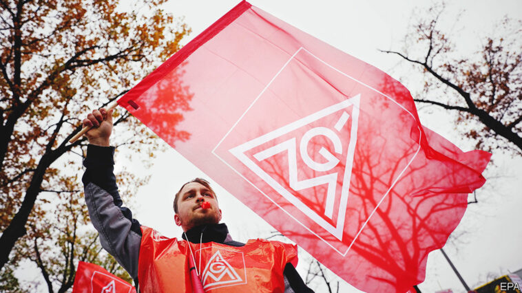 Mandatory Credit: Photo by CLEMENS BILAN/EPA-EFE/Shutterstock (13627429d)A participant waves a flag of German metalworkers' union IG Metall during a warning strike of the Mercedes-Benz plant employees in Berlin, Germany, 17 November 2022. German metalworkers' union IG Metall demands a payment rise of eight percent.Warning strike of German trade union IG Metall in Berlin, Germany - 17 Nov 2022