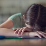 Teenage girl with head in hands, fed up with school homework