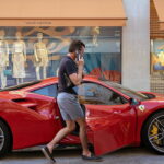 A driver returns to his red Ferrari parked on the pavement outside the Louis Vuitton store in Bond Street, on 12th August 2022, in London, England. After the Bank of England raised interest rates to 1.75%, there is a certainty that Britain will be in recession by the fourth quarter of 2022 and with inflation to climb further. (Photo by Richard Baker / In Pictures via Getty Images)