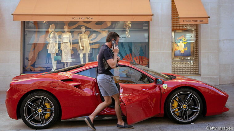 A driver returns to his red Ferrari parked on the pavement outside the Louis Vuitton store in Bond Street, on 12th August 2022, in London, England. After the Bank of England raised interest rates to 1.75%, there is a certainty that Britain will be in recession by the fourth quarter of 2022 and with inflation to climb further. (Photo by Richard Baker / In Pictures via Getty Images)