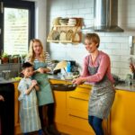 Woman flipping pancake in kitchen with family