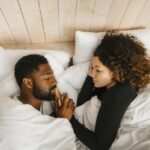 Directly above view of couple sleeping on bed in hotel