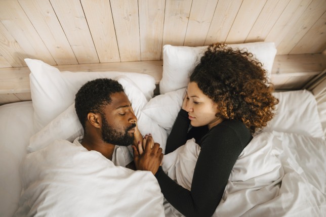 Directly above view of couple sleeping on bed in hotel