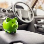 Green piggy bank money box inside car, vehicle purchase, insurance or driving and motoring cost