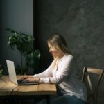 A middle-aged woman sitting at the table in front of a laptop