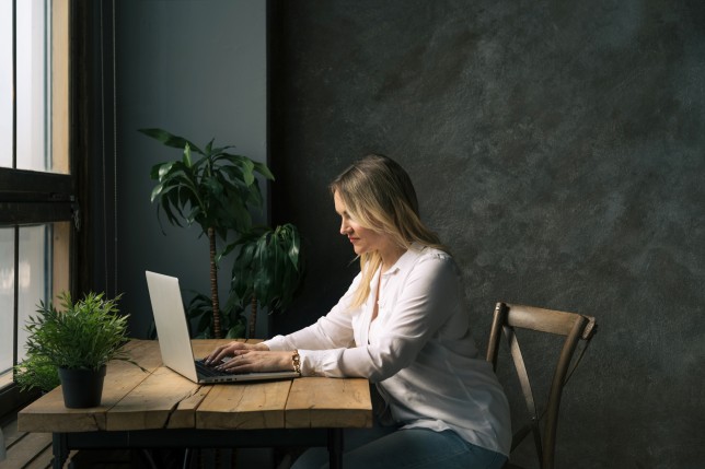 A middle-aged woman sitting at the table in front of a laptop