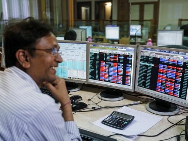 A broker laughs while speaking to a colleague, as they trade on their computer terminals at a stock brokerage firm in Mumbai