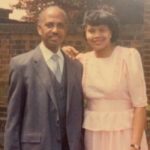 Shaun Flores' parents, Carlos and Yolande Flores, standing outside in front of a brick wall and smiling at the camera.