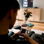 Teenage boy using smart phone while sitting on sofa at home