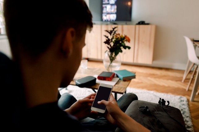 Teenage boy using smart phone while sitting on sofa at home