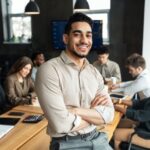 Young bearded businessman sitting on desk and posing