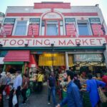 A picture of Tooting Market in the day time busy with vendors and visitors