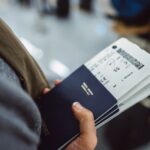 Woman’s hands holding passports boarding passes of her family while waiting at the check-in counter in the airport