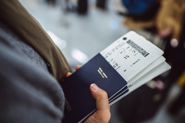 Woman’s hands holding passports boarding passes of her family while waiting at the check-in counter in the airport