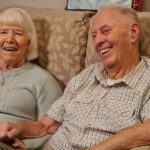 Ron and Sheila sitting on a sofa, holding hands