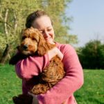 Woman cuddling her dog in a field