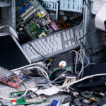 Stacks of old computers and other IT hardware symbolizing the disorganization that fuels the IT e-waste crisis.