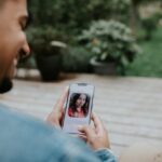 A man holds a smart phone and browses a dating app