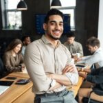 Young bearded businessman sitting on desk and posing after a level results day