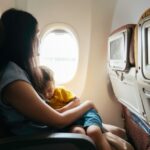 mother holding baby son on airplane